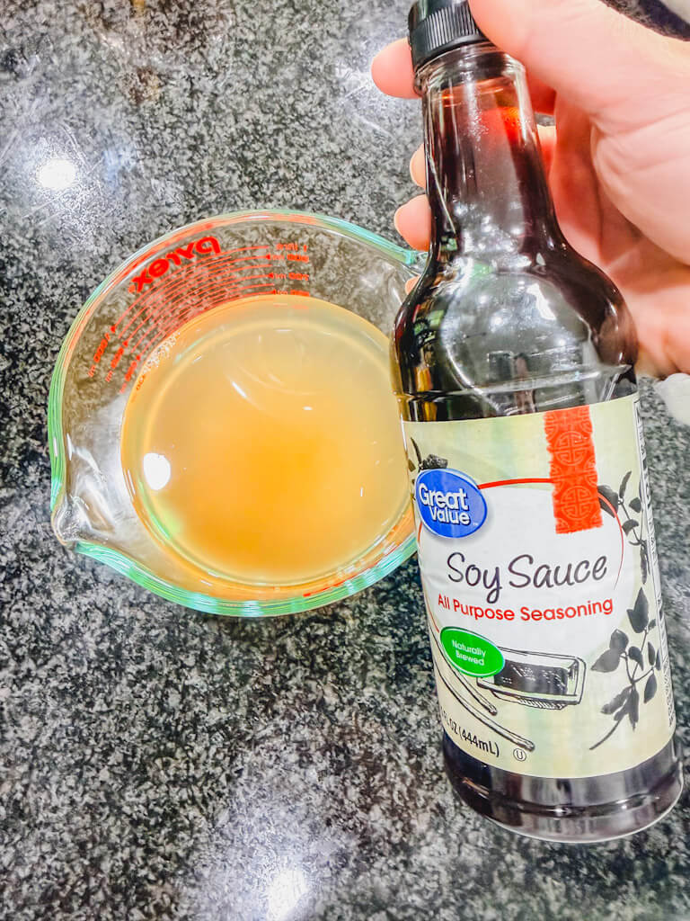 Soy sauce being added to teriyaki sauce mixture in measuring cup.