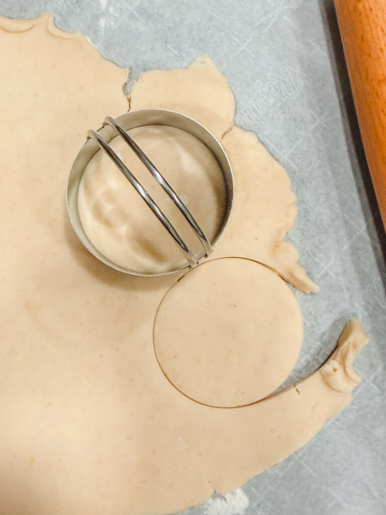 Cookie dough rolled out to a quarter inch thickness and a cookie cutter has been placed on top of the dough.