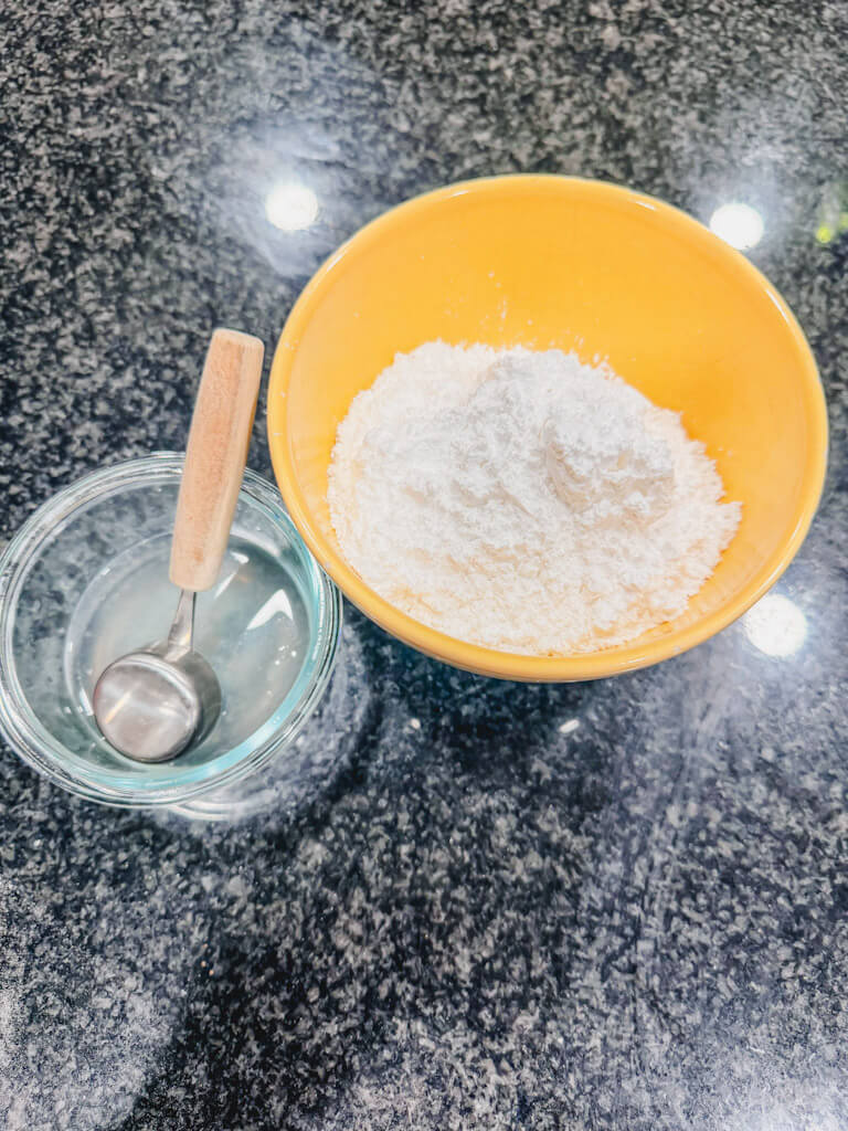 Ingredients for the lemon glaze on a black counter top.
