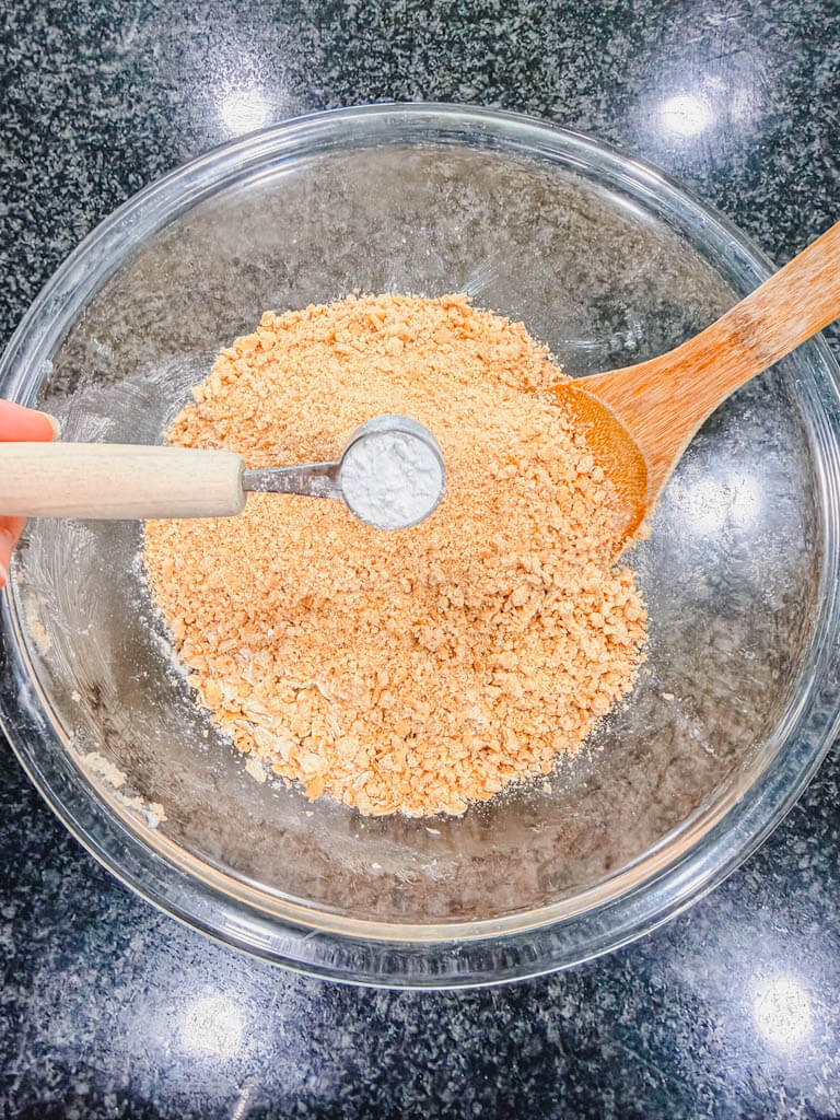 Baking powder in a teaspoon measuring spoon about to be added to the bowl.