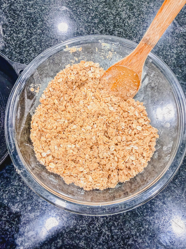 Graham cracker crumble mixture combined in a glass mixing bowl.