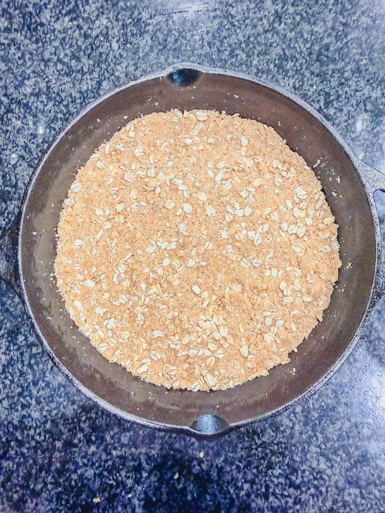 Graham cracker crumble mixture pressed into the bottom of a cast iron skillet to form the crust.