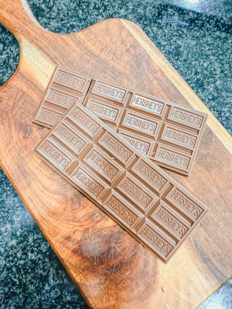 Milk chocolate bars on a wooden cutting board for Cast Iron Skillet S'mores Pie.