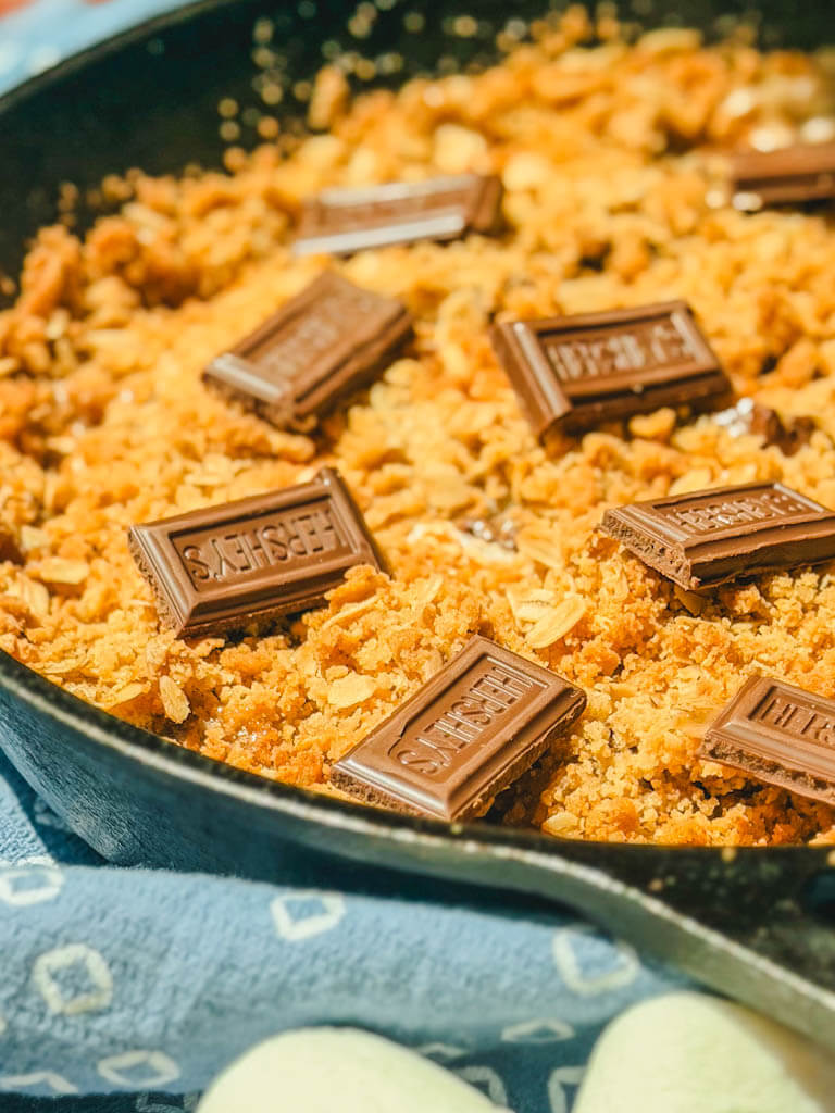 close up shot of the skillet s'mores with a blue kitchen towel around the skillet.