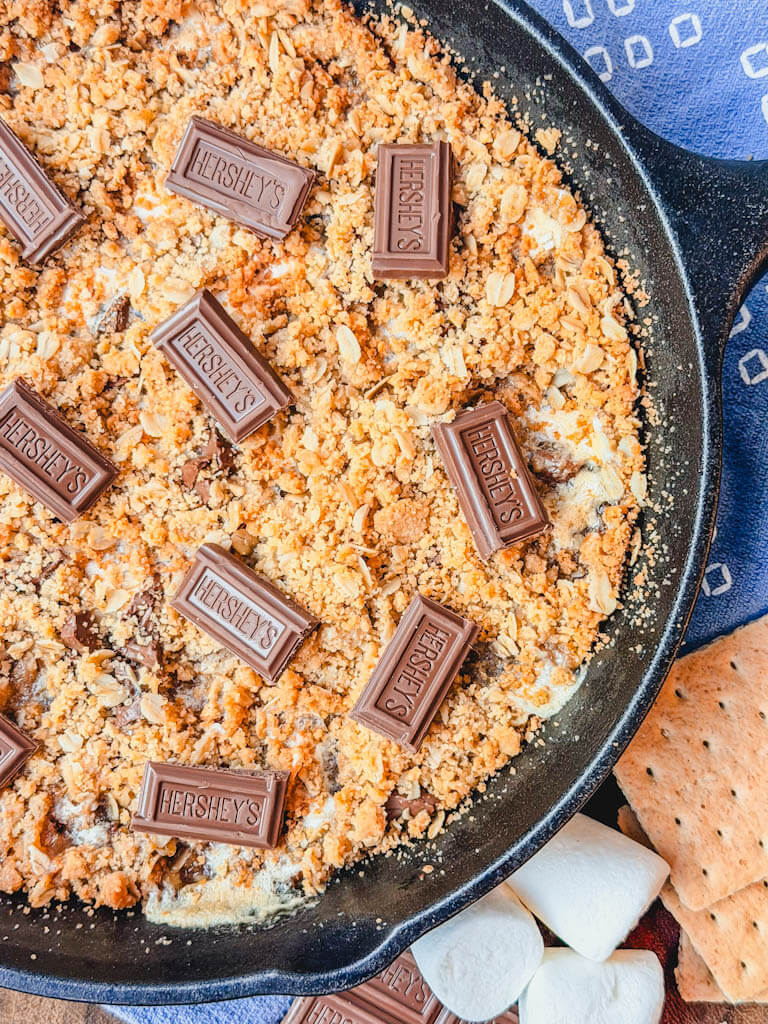 Cast Iron Skillet S'mores Pie baked until golden brown in a cast iron skillet next to graham crackers and chocolate bars.