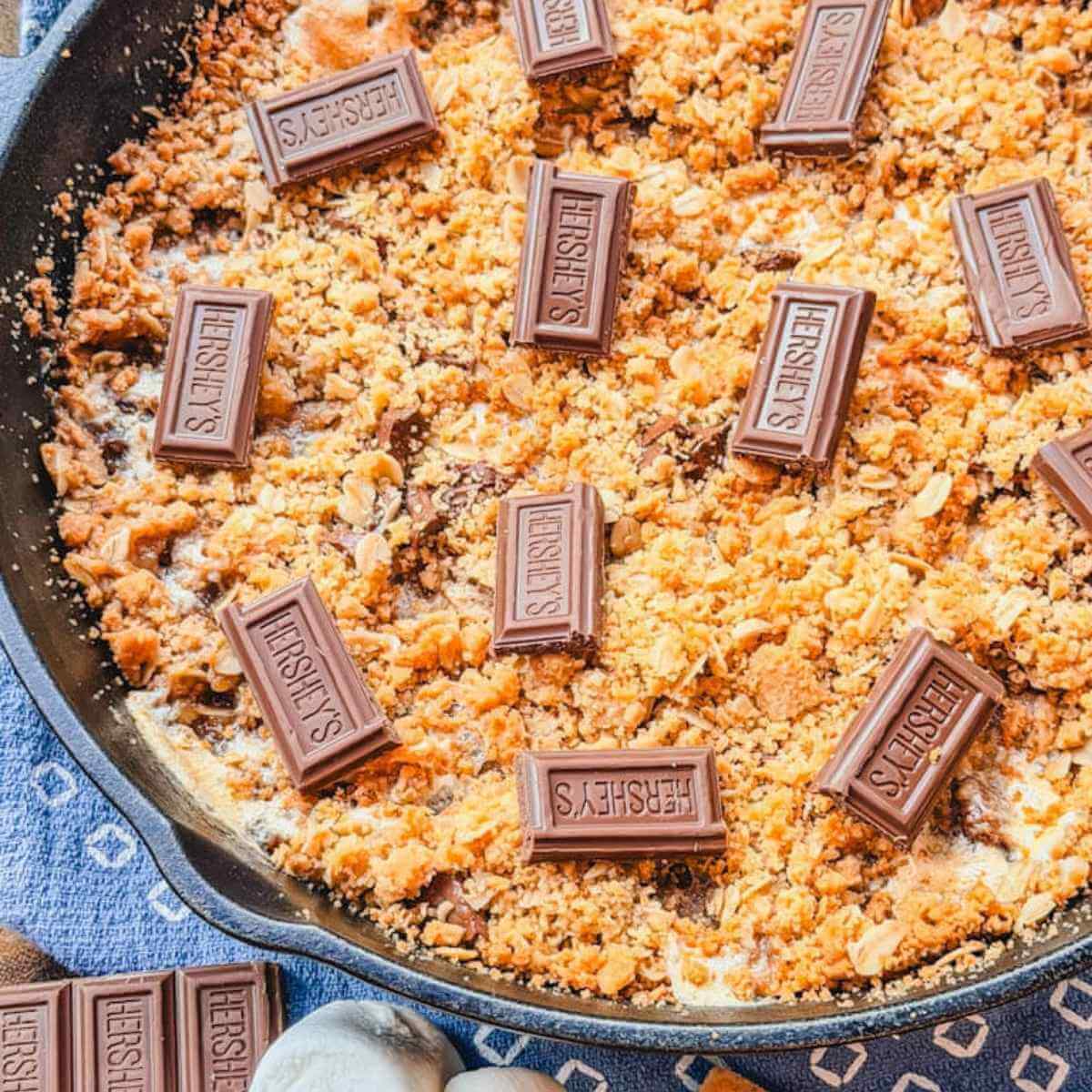 Overhead view of homemade Cast Iron Skillet S'mores Pie topped with chocolate pieces and baked in a cast iron skillet.
