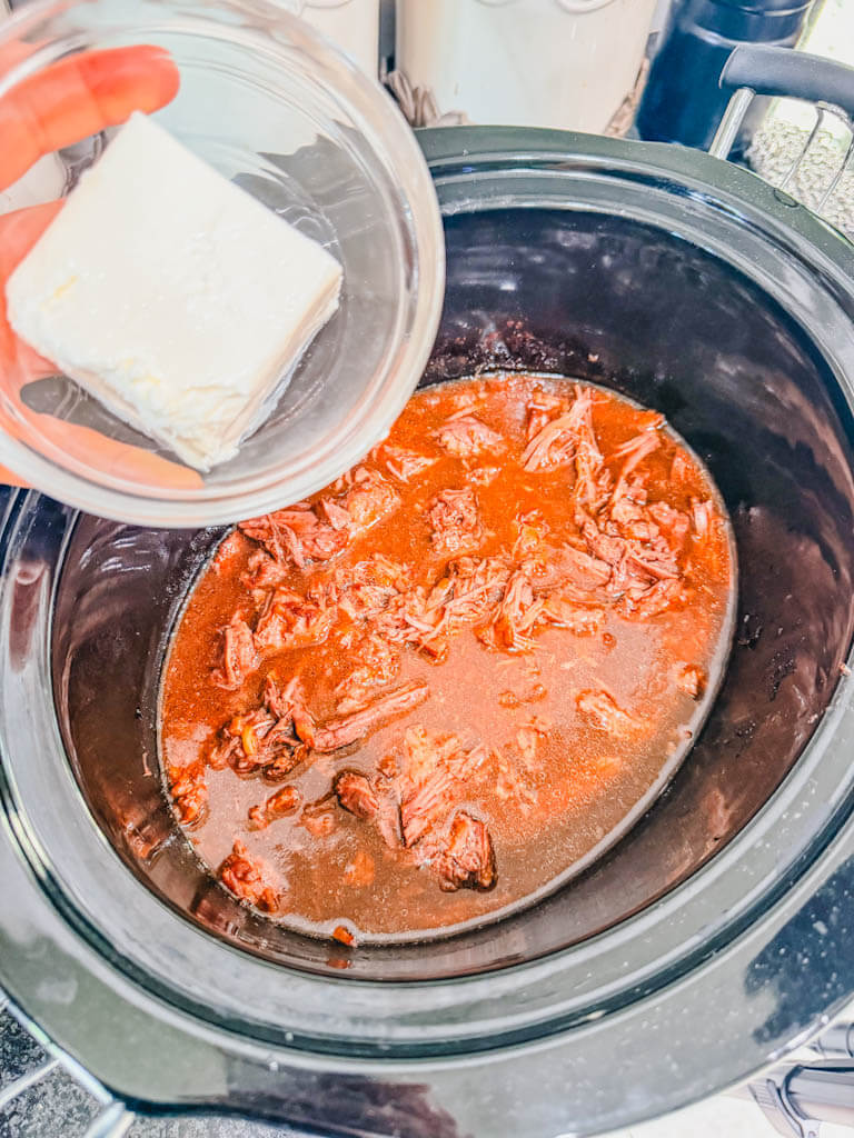 a small bowl holding cream cheese over the slow cooker.