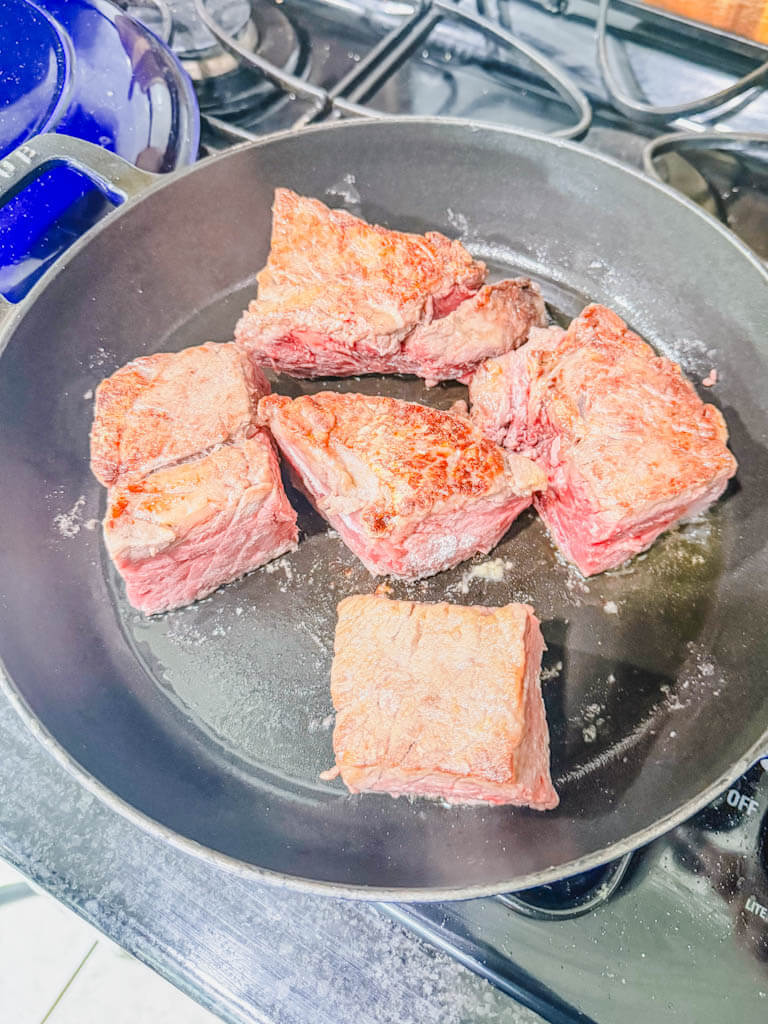 beef chuck browning in a large cast iron skillet.