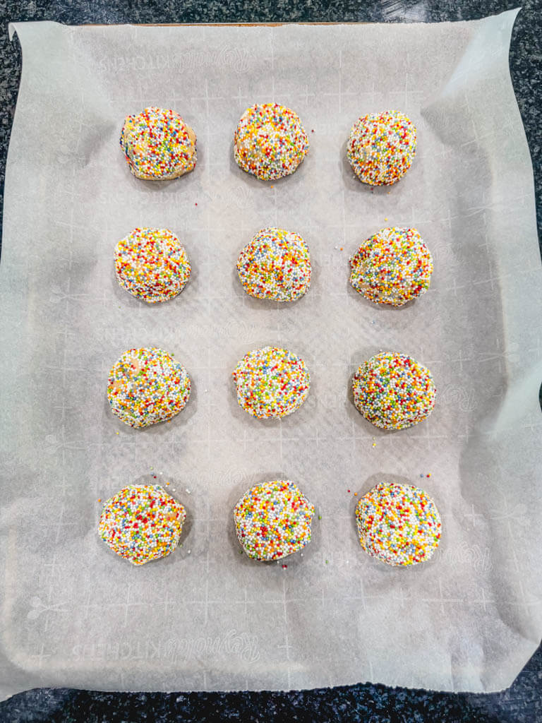 cookie dough balls that have been rolled in rainbow sprinkles ready to chill in the fridge.