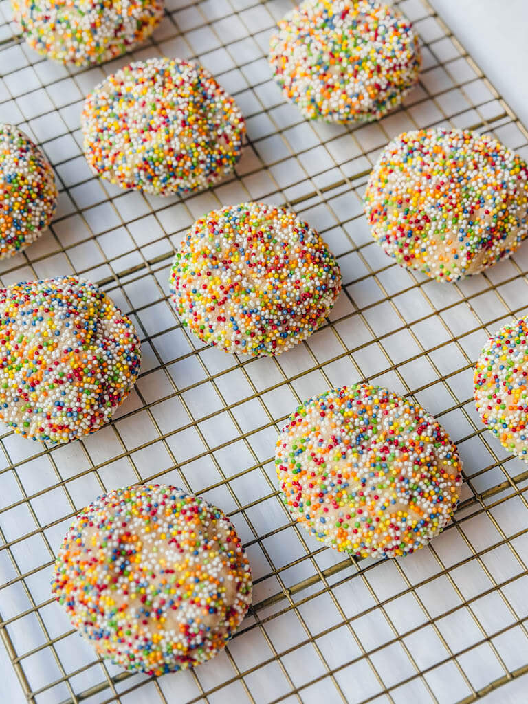 sprinkle sugar cookies resting on a wire rack after baking.