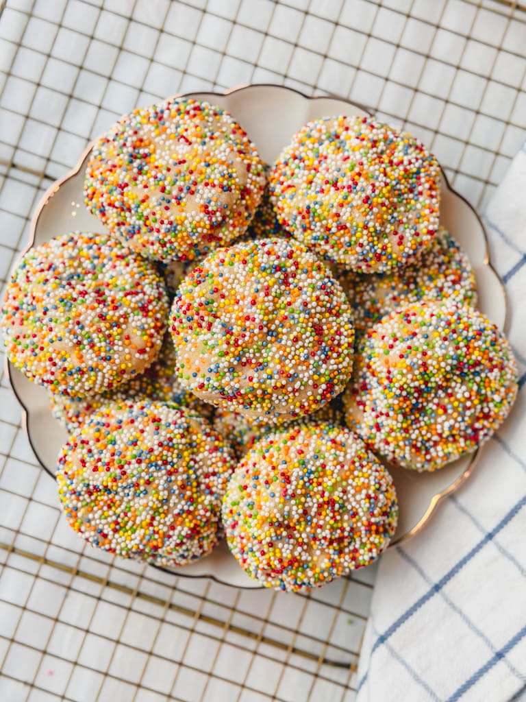 overhead view of sprinkle sugar cookies on a plate on top of a wire rack.