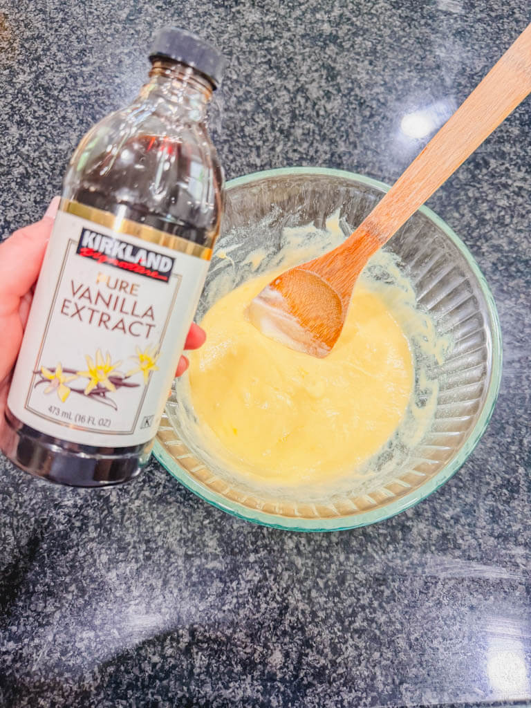 A bottle of vanilla extract being held over the mixing bowl.