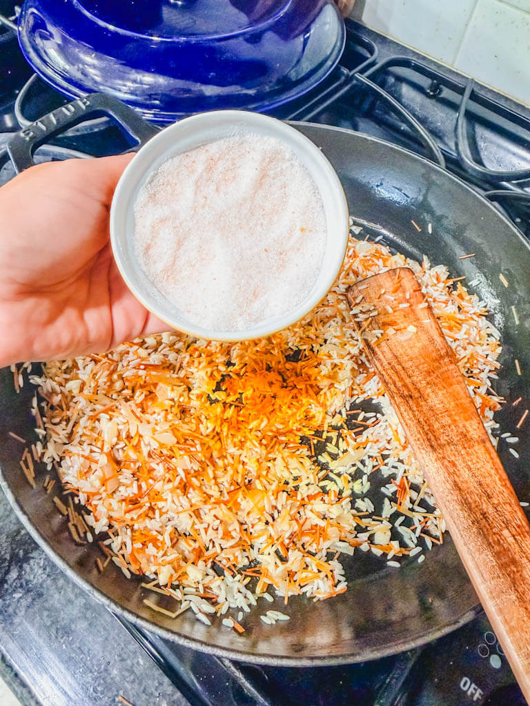 A small bowl of salt being held over the skillet.