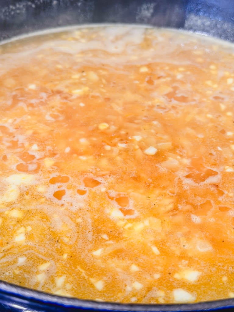 Rice pilaf simmering in seasoned chicken broth before covering.