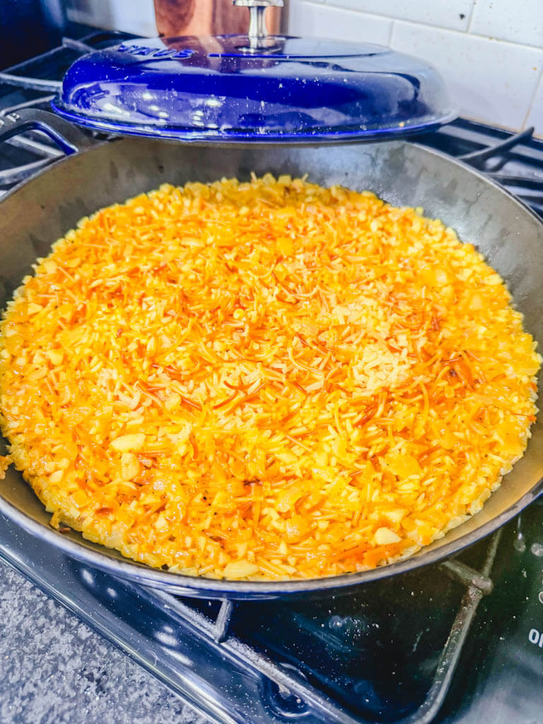 Homemade rice pilaf fully cooked in a skillet before fluffing.