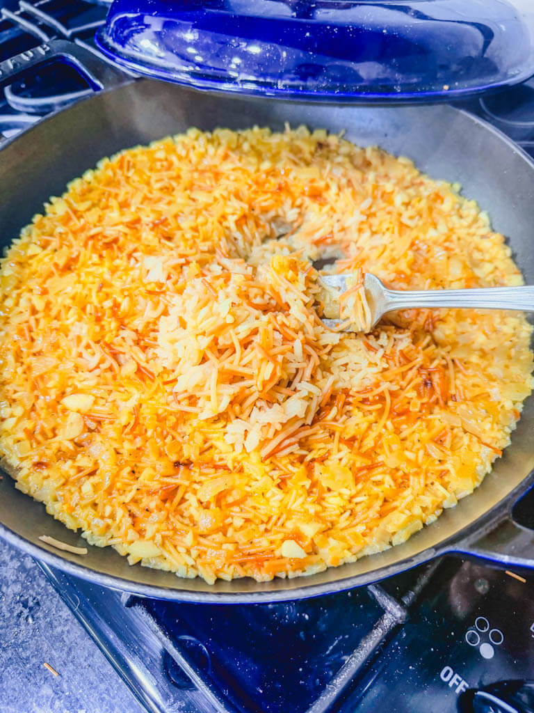 Fork fluffing homemade rice pilaf after resting.