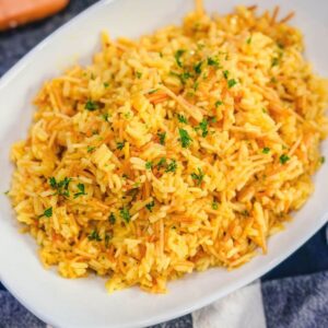 Close up of homemade rice pilaf topped with parsley in a white serving dish.