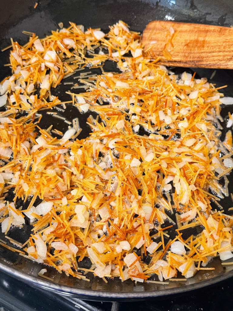 Toasted vermicelli and onions cooking together in butter.