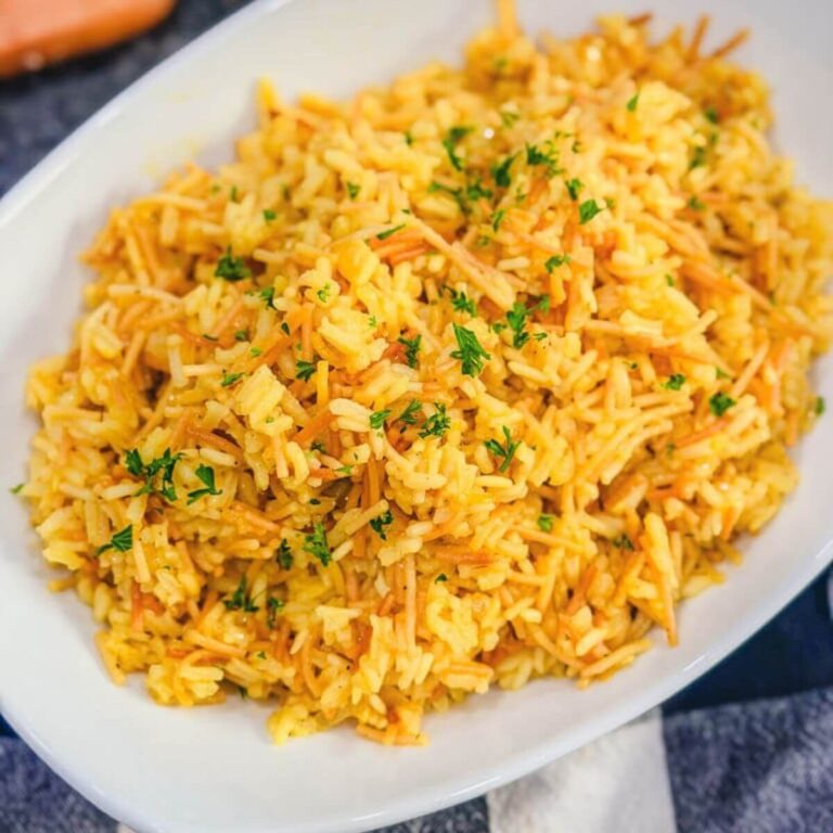 Close up of homemade rice pilaf topped with parsley in a white serving dish.