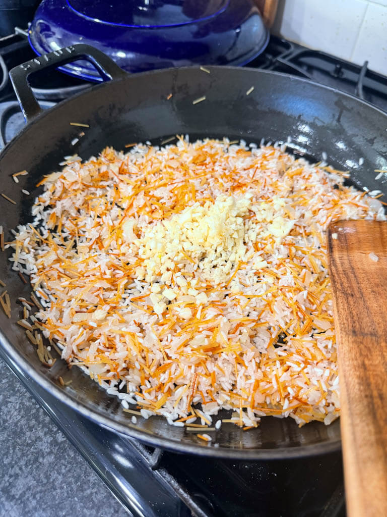 Minced garlic added to toasted rice for homemade rice pilaf.