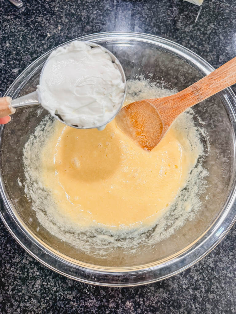 Sour cream being added to the peach muffin batter.