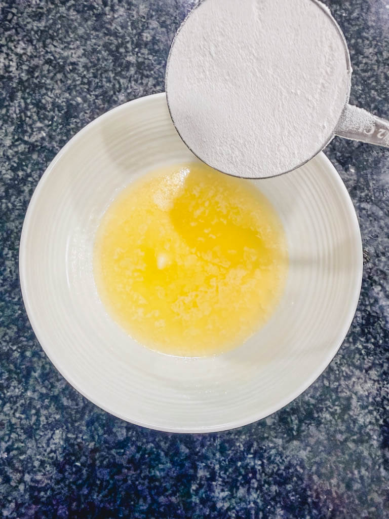 Melted butter with flour added in a bowl to begin making the cinnamon streusel topping.