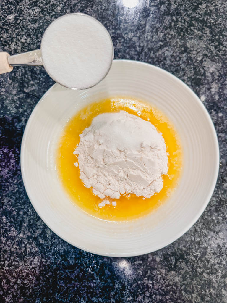Granulated sugar being added to the streusel mixture.