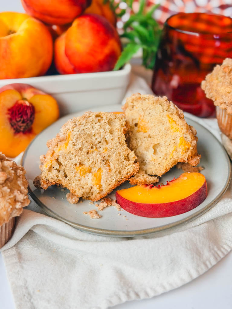 a peach muffin sliced in half to see the chunks of peach inside the muffin.