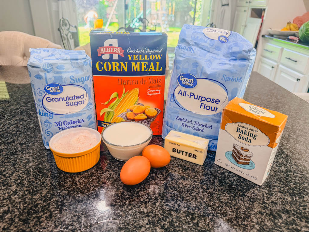 Ingredients for Homemade Sweet Cornbread laid out on a black counter.