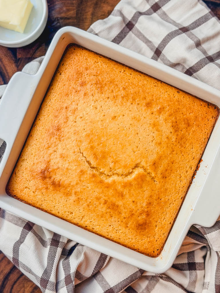 Golden homemade sweet cornbread baked in a white ceramic baking dish.