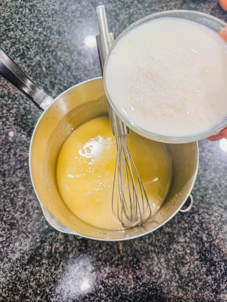 Homemade buttermilk being poured into the saucepan with butter and sugar.