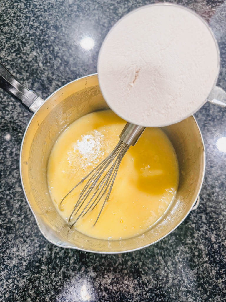 All-purpose flour being added to the cornbread batter.