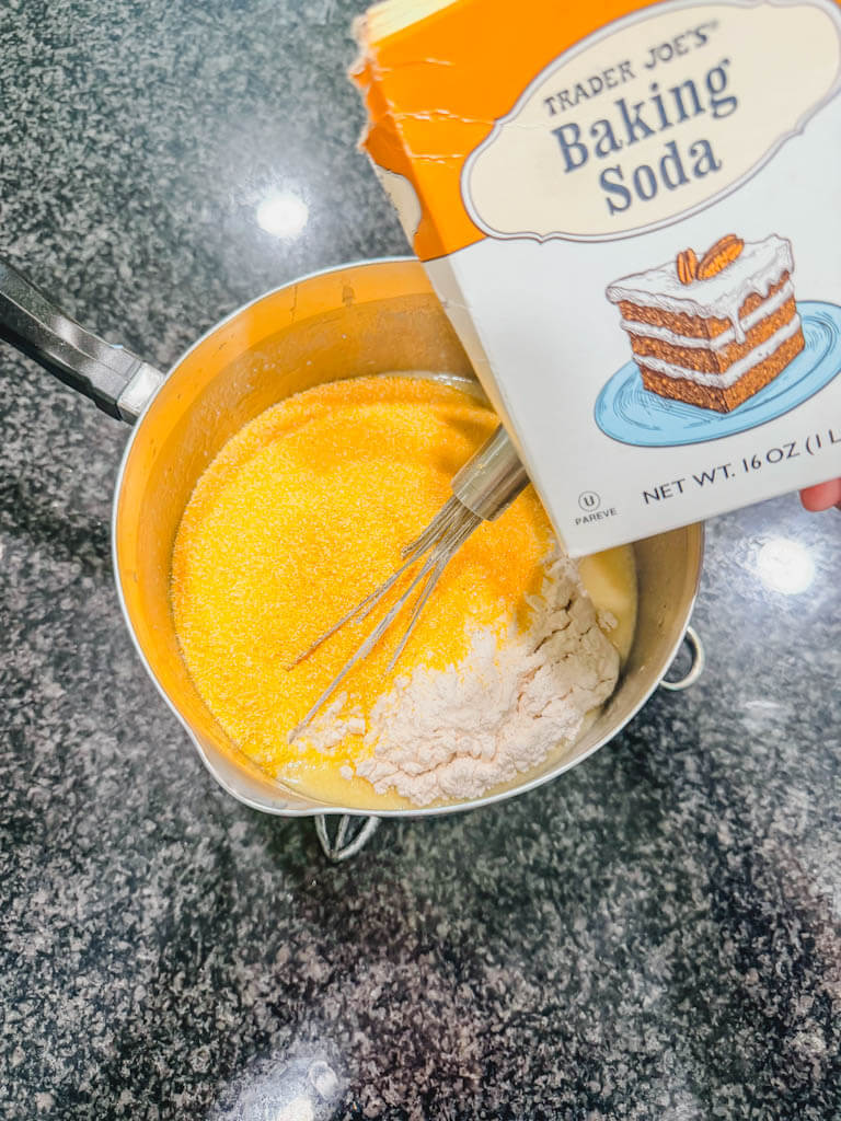A box of baking soda being held over the saucepan.