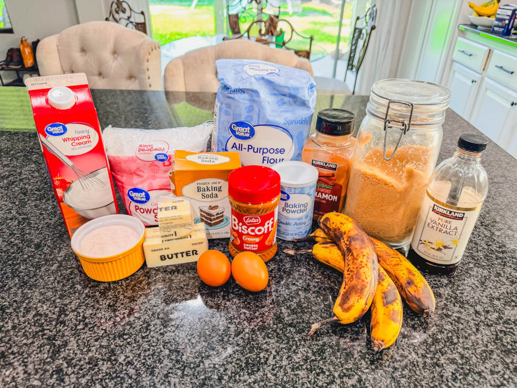 Ingredients for homemade Biscoff banana bread with brown sugar icing arranged on a kitchen counter.