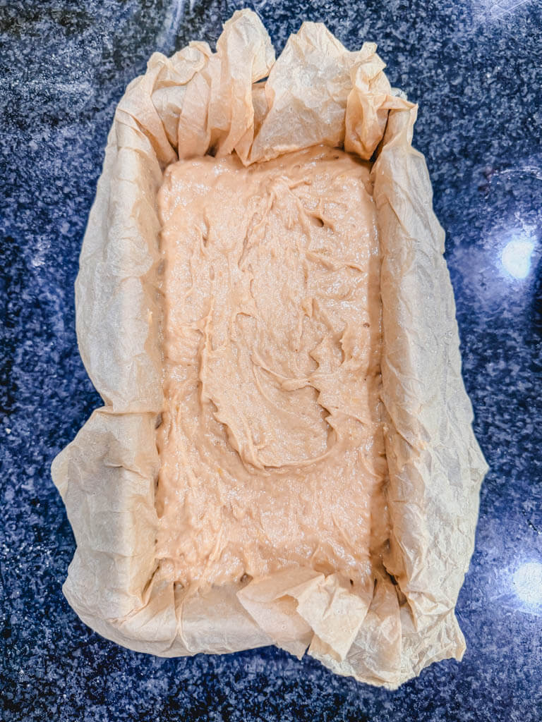 Biscoff banana bread batter spread evenly in a parchment-lined 9x5-inch loaf pan.