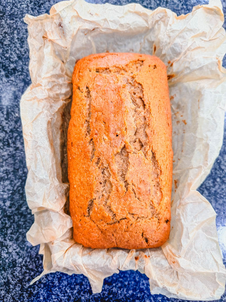 Freshly baked Biscoff banana bread cooling in a parchment-lined loaf pan.