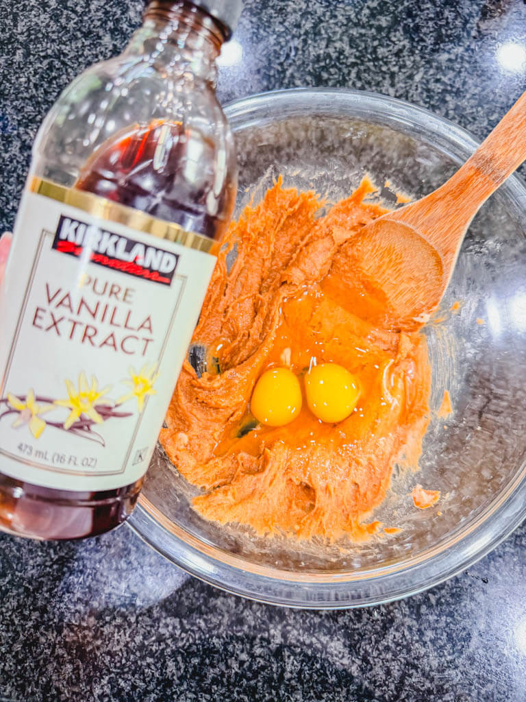 Eggs and vanilla extract being added to the Biscoff banana bread mixture.