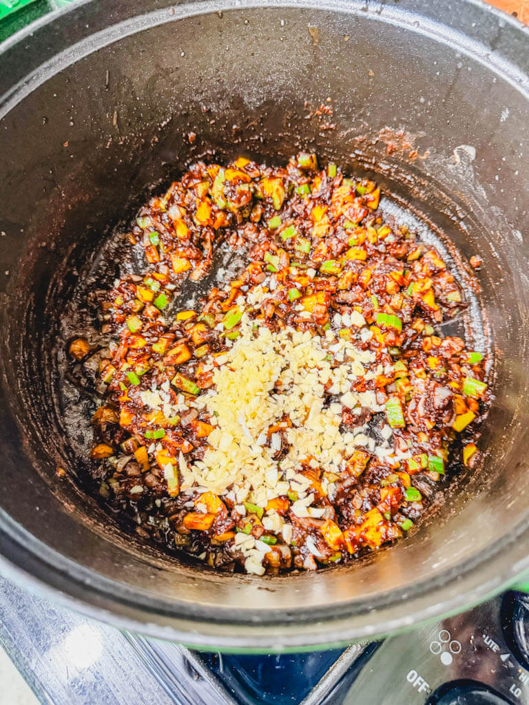 Minced garlic added to sautéed onion, celery, and bell pepper in dark gumbo roux.