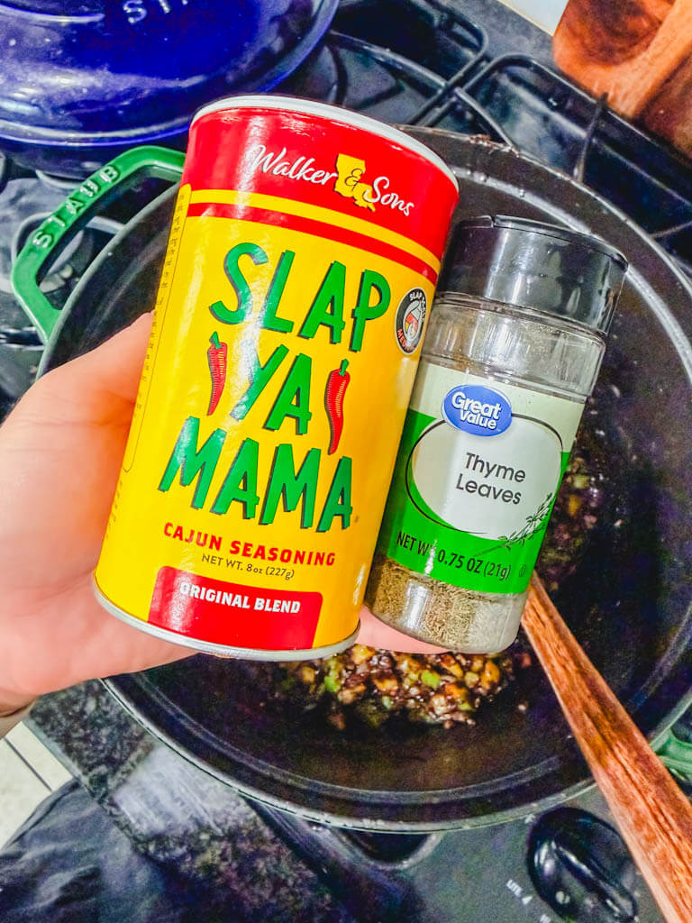 Slap Ya Mama Cajun seasoning and dried thyme being used to season homemade gumbo.