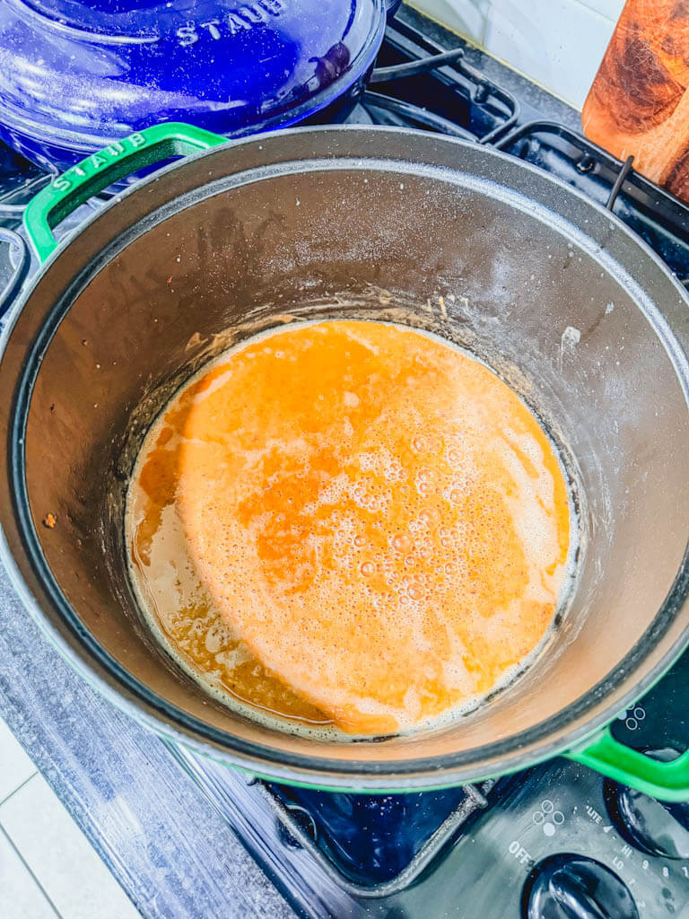 Golden brown roux cooking in a Dutch oven for shrimp and sausage gumbo.