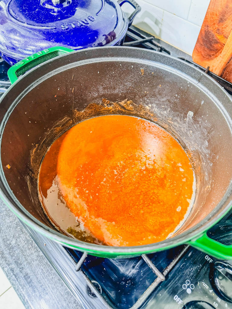 Gumbo roux cooked to a deep golden peanut butter color in a Dutch oven.