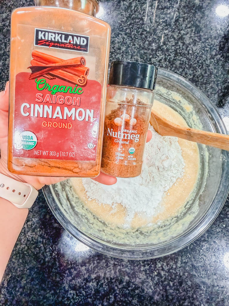 Ground cinnamon and nutmeg being added to banana pecan muffin batter.