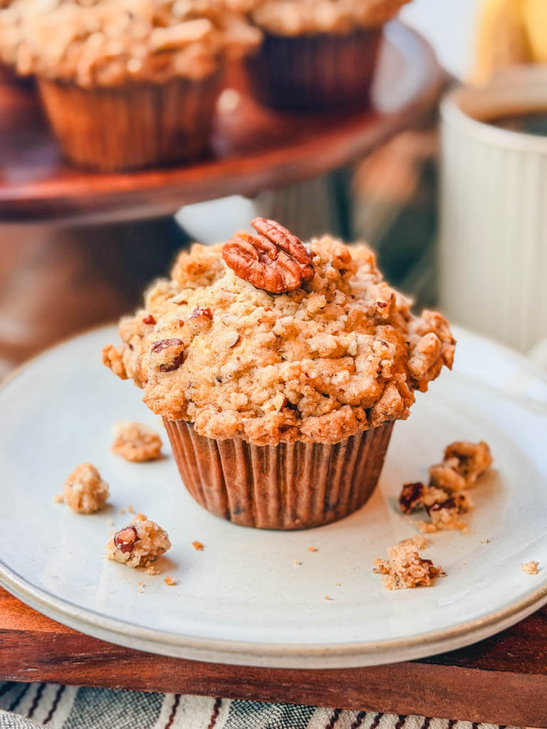 Bakery-style banana pecan muffin topped with a crunchy pecan streusel and whole pecan.